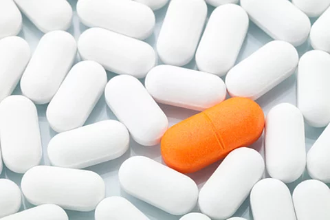 Orange Tablette inmitten von weißen Tabletten