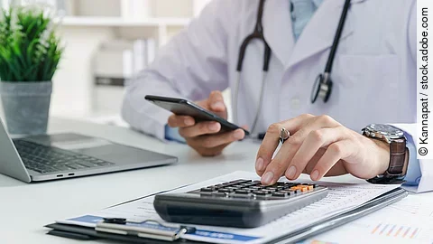 Doctor physician calculate medical healthcare fee costs and revenue, Practitioner using calculator at Clinic.