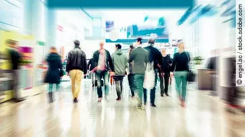 Verschwommene Geschäftsleute Pendler Business Menschen gehen durch ein Einkaufszentrum mit Geschäften und breiten Laufwegen.