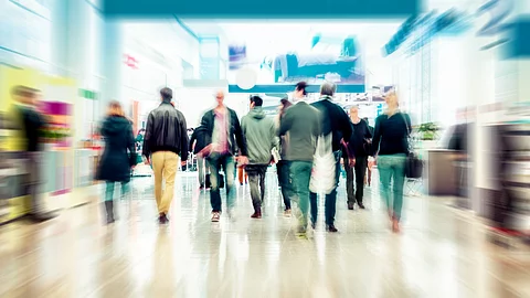 Verschwommene Geschäftsleute Pendler Business Menschen gehen durch ein Einkaufszentrum mit Geschäften und breiten Laufwegen.