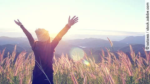 Happy Woman Enjoying Nature on grass meadow on top of mountain c