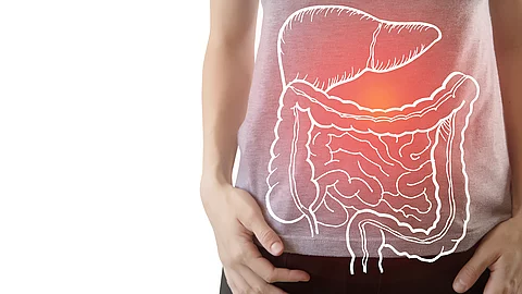 Person im grauen T-Shirt mit grafischer Darstellung des Verdauungstrakts auf dem Bauch. Die Leber und der Darm sind weiß skizziert, ein roter Lichtpunkt markiert den Bereich der Leber.