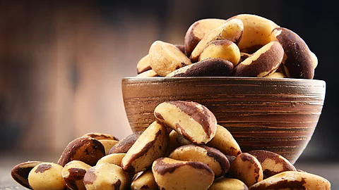 Bowl with Brazil nuts on wooden table