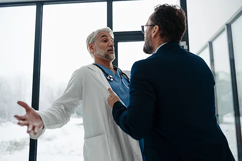 Violence against health workers. Patient is aggressive, have conflict with doctor in hospital corridor. Visitor holding doctor by coat, screaming, threatening him.