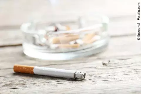 Cigarette with ash on grey wooden table