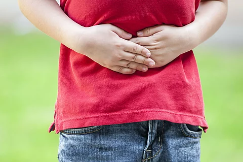 Child with stomach ache, little boy holding hands on his belly.