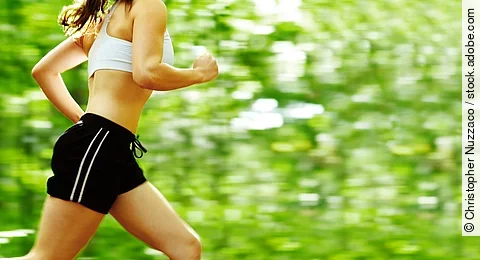 Beautiful young woman runner in a green forest.