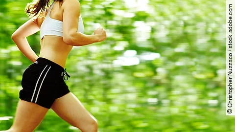 Beautiful young woman runner in a green forest.
