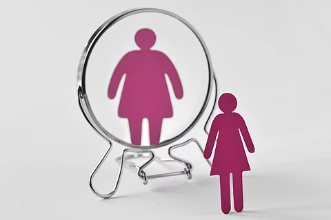 Slim paper woman looking in the mirror and seeing herself as a f Slim paper woman looking in the mirror and seeing herself as a f