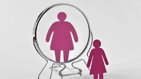Slim paper woman looking in the mirror and seeing herself as a f