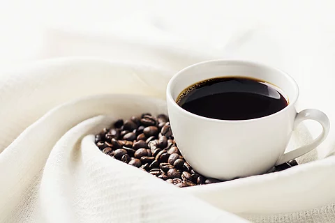 eine Tasse schwarzer Kaffee und Kaffeebohnen