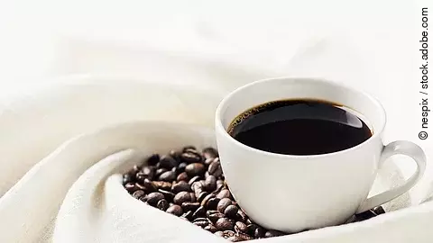 eine Tasse schwarzer Kaffee und Kaffeebohnen