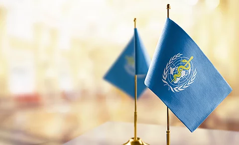 Small flags of the World Health Organization WHO on an abstract blurry background