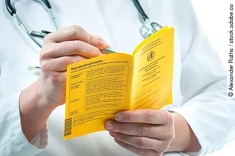 Impfbuch - ein Arzt nimmt Eintragungen vor