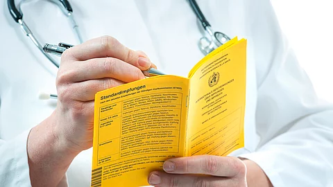 Impfbuch - ein Arzt nimmt Eintragungen vor
