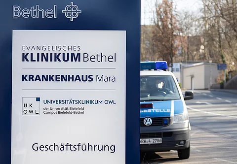 Evangelisches Klinikum Bethel in Bielefeld – hier soll ein Assistenzarzt über Jahre hinweg Patientinnen missbraucht haben. Nun stehen Führungskräfte wegen mutmaßlicher Versäumnisse vor Gericht. Ein Fahrzeug der Polizei steht an einem Gebäude der Geschäftsführung des Evangelischen Klinikums Bethel.