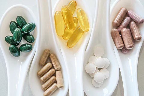 Top view of natural vitamin supplement on white spoon as frame o
