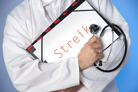 Arzt hält Streikschild vor der Brust